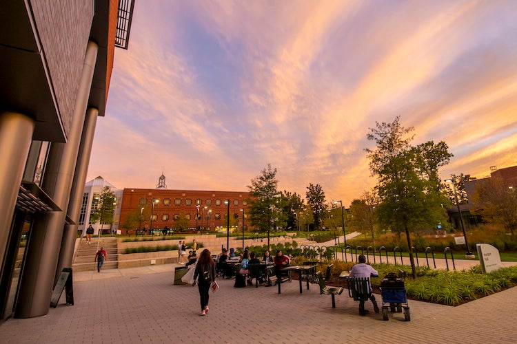 students sit at tables outside on Wilkins Plaza