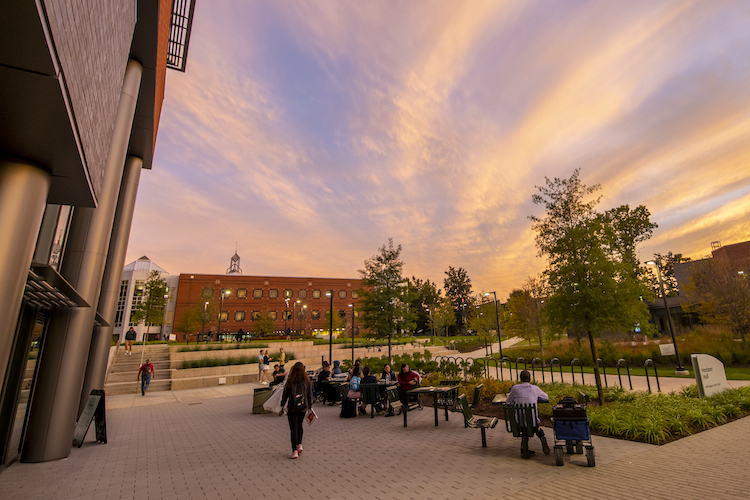 students sit at tables outside on Wilkins Plaza